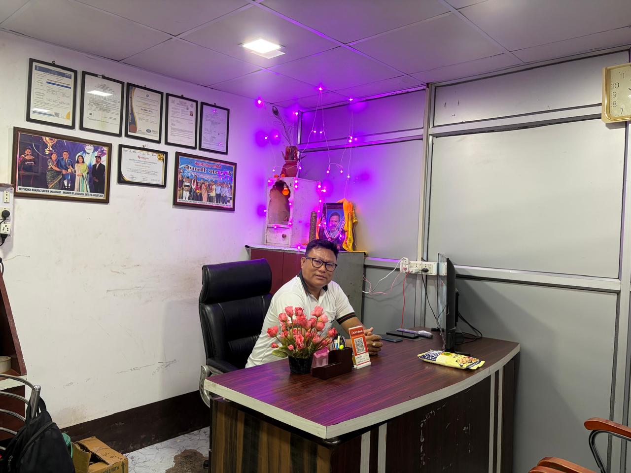 The founder of Yumme Momos Manufacturer at the Jamshedpur office, beside the company’s framed certifications and awards